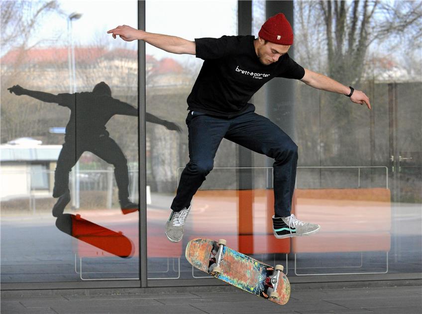 Skater Robert Born spiegelt sich beim Kickflip zusammen mit dem Schloss Hohentübingen in der Scheibe des Sparkassen-Carrés. Bild: Franke