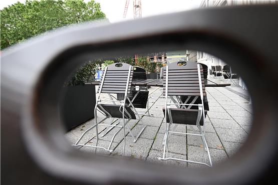 Stühle in einer Außengastronomie sind bei regnerischem Wetter hochgeklappt. Foto: Bernd Weißbrod/dpa