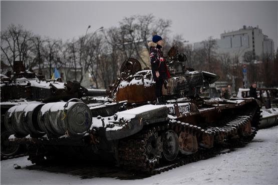 Szene aus dem Kriegsalltag: Ein Junge steht in der ukrainischen Hauptstadt Kiew auf einem zerstörten russischen Panzer. Die Autorin Ljudmila Ulitzkaja wandte sich in einem Artikel gegen den russischen Angriff – und musste deswegen ihre Heimat verlassen. Foto: Daniel Cole/AP/dpa