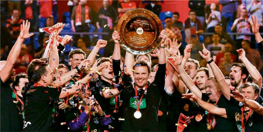 Triumph: Deutschlands Handball-Nationaltrainer Dagur Sigurdsson reckt inmitten seiner Spieler den EM-Pokal in die Höhe. Foto: dpa