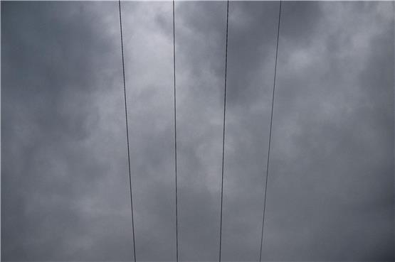Über den Leitungen eines Strommastes durchziehen Wolken den Himmel. Foto: Pia Bayer/dpa