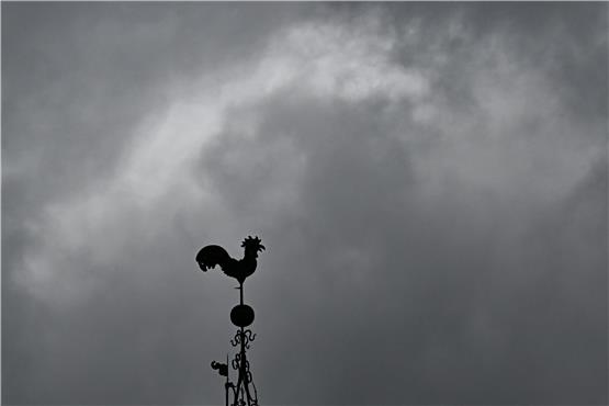 Über einem Wetterhahn schweben dunkle Regenwolken. Foto: Bernd Weißbrod/dpa