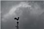 Über einem Wetterhahn schweben dunkle Regenwolken. Foto: Bernd Weißbrod/dpa
