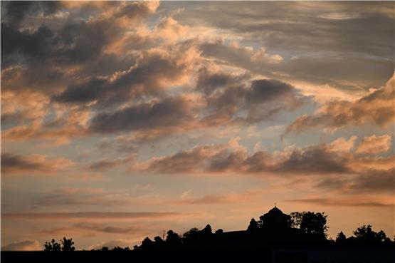 Von der aufgehenden Sonne rot angestrahlt werden Wolken über dem Württemberg bei Stuttgart. Foto: Bernd Weißbrod/dpa/Symbolbild