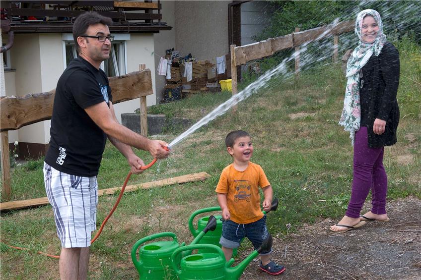 Was gibt es an einem heißen Sommertag Schöneres als kühles Wasser aus dem Gartenschlauch? Der kleine Asem (hier mit Mostafa Hamki und seiner Mutter Rahaf Breiki) scheint jedenfalls sehr begeistert.