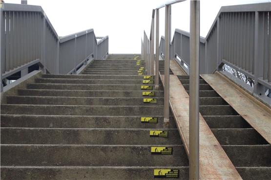 „Weg mit den Barrieren“- Aufkleber hatte Lothar Gugel auf Stufen und Geländer des Stegs am Ergenzinger Bahnhof angebracht. Insgesamt 168 Stufen müssen überwunden werden, um auf den zweiten.Bahnsteig zu gelangen. Für Menschen im Rollstuhl trotz Rampe kaum zu bewältigen. Bild: Bernhard