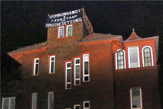 „Wohnungsnot + Leerstand = Hausbesetzung“ steht auf dem Transparent, das ein Trupp Besetzer entrollt hat. Bild: Sommer