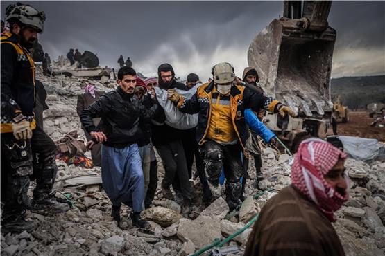 Zivilisten und Mitglieder des syrischen Zivilschutzes führen Such- und Rettungsmaßnahmen in den Trümmern eines zerstörten Gebäudes durch. Foto: Anas Alkharboutli/dpa