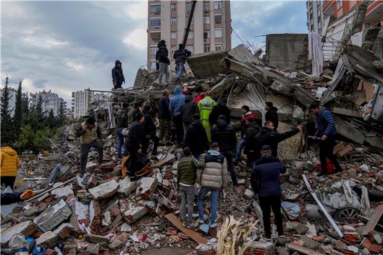 Zivilisten und Notfallteams suchen nach Menschen in den Trümmern eines zerstörten Gebäudes in der türkischen Stadt Adana.  Foto: Khalil Hamra/AP/dpa